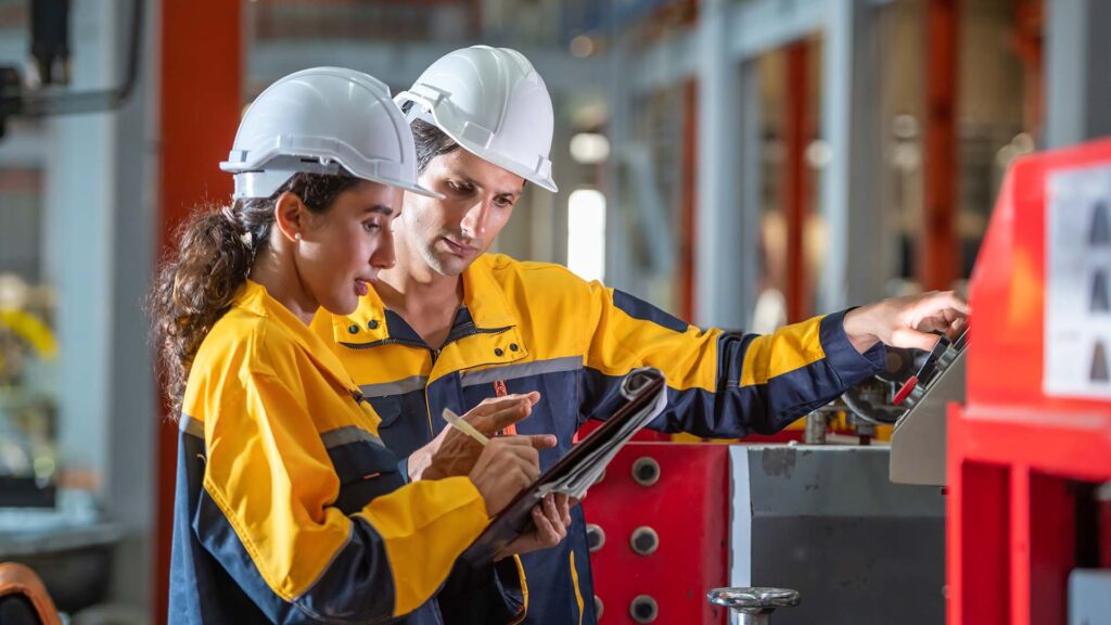 Factory workers looking and operating heavy machinery