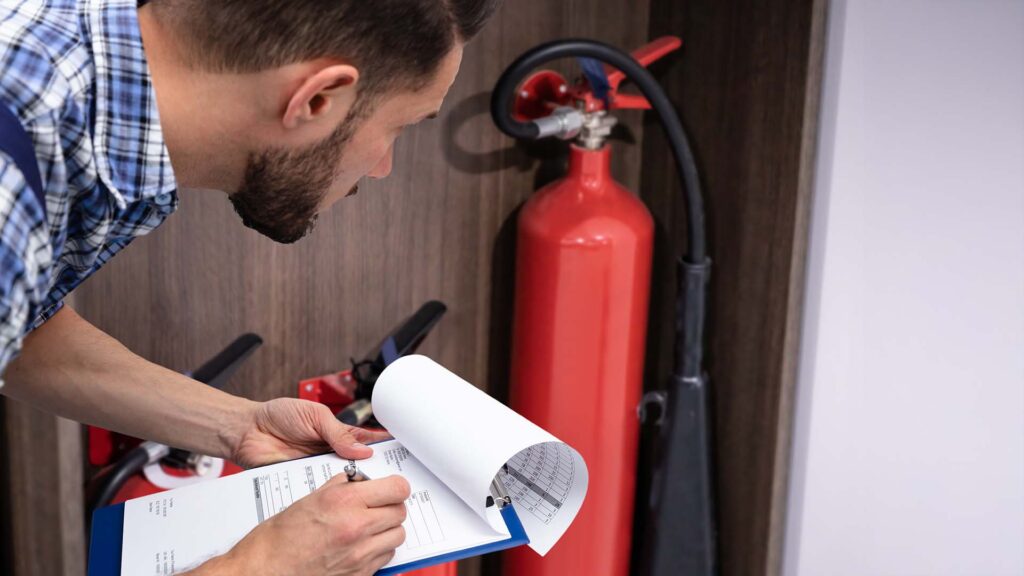 Close of a person learning down doing annual review of fire extinguisher