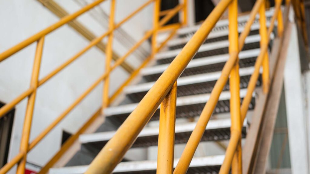 Banister handrail with yellow painting of stairway platform at the factory place