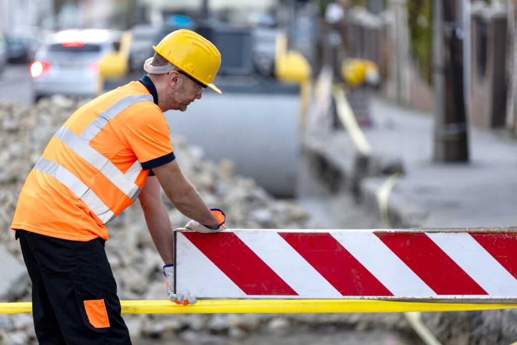 Construction worker adjusting a barrier on streets under repair