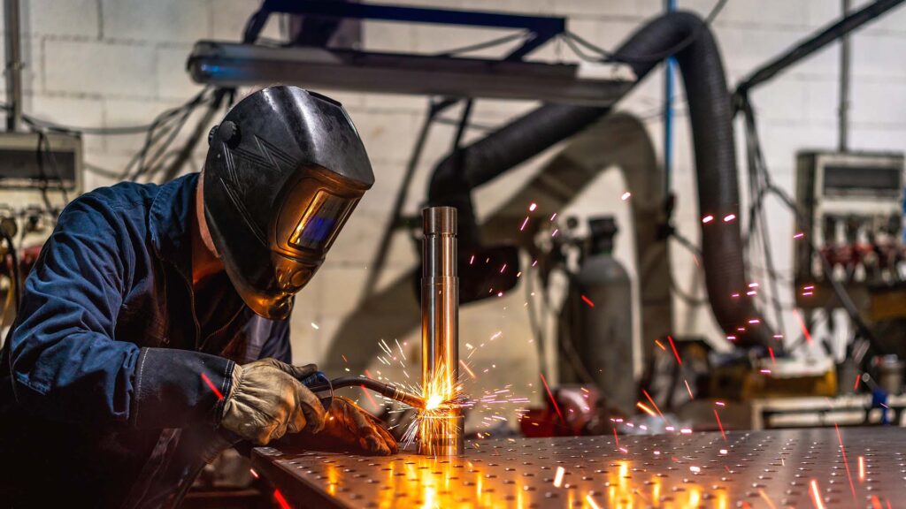Close of a welder operating a welding machine, sparks flying in a factory