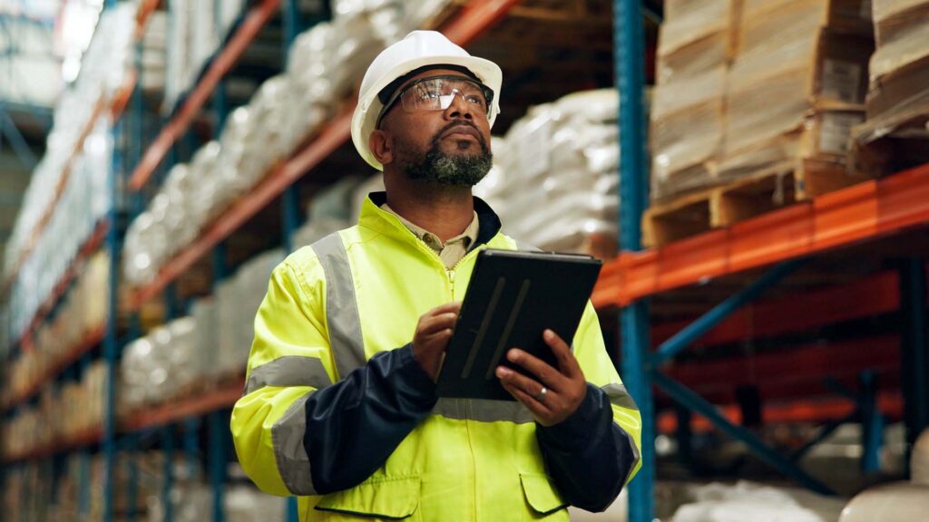 Man on tablet in a storage facility wearing safety vest