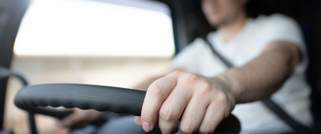 Close up of truck drivers hand in focus while the rest of the background is out of focused, including him